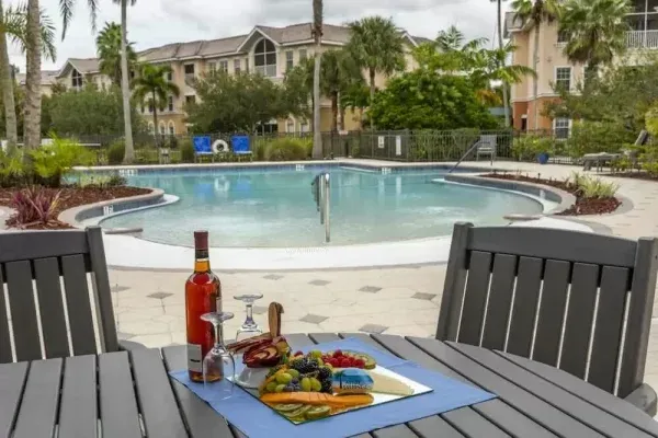 Aston Gardens at Pelican Pointe pool with charcuterie board and bottle of wine