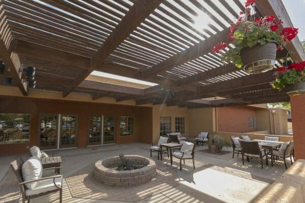 Chandler Health Care rear porch with large trellis overhead and stone fir pit