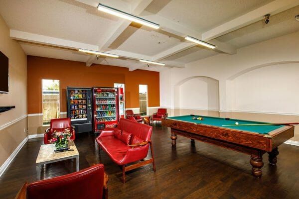 Entertainment room at Pacific Pointe. Includes a pool table, vending machines, large screen tv with seating area.