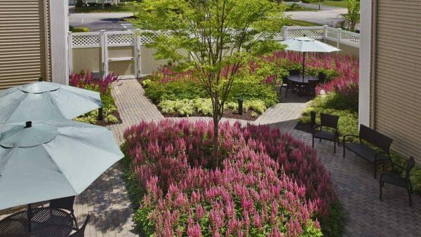 Walking paths around a flower bed and trees at Atria Crossroads Place