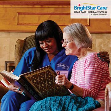 BrightStar Care of Chesapeake caregiver looking at photo album with senior woman