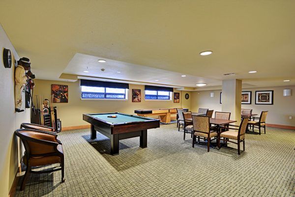 A billiards table, card tables and shuffleboard table in the game room at Brookdale West Seattle