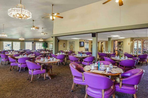 Bright purple chairs and many tables in the Longmont Regent community dining room