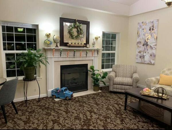 Sitting area with chair, table, two windows, fireplace and toy truck in front of fireplace at Mountain View Assisted Living and Memory Care