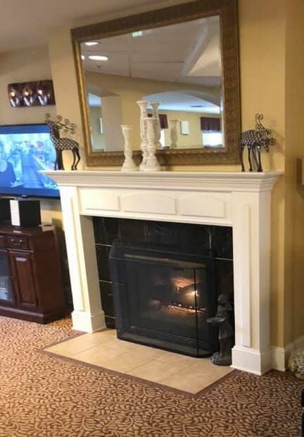 Fire in a fireplace with a tv on the right and a mirror above the fireplace at Siskiyou Springs Assisted Living & Memory Care