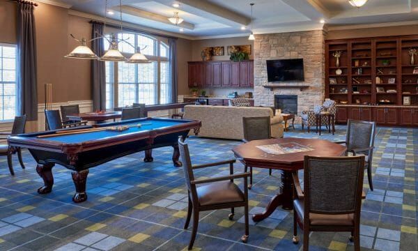 Resident game room with pool and card tables at Waltonwood Lake Boone