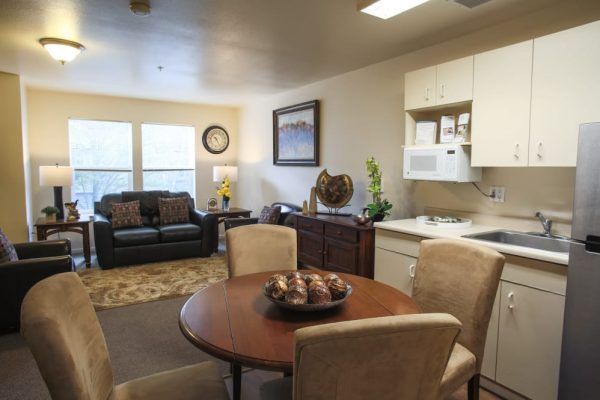 The living room, dining table for four and kitchenette of a model apartment at GenCare Lifestyle Federal Way