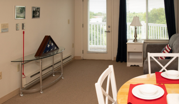 The living room, with a door onto a balcony, and dining area in a model apartment at Howard Village