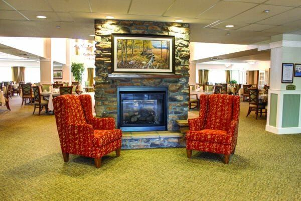 Two arm chairs in front of a fireplace in the Rigden Farm Retirement Community lobby