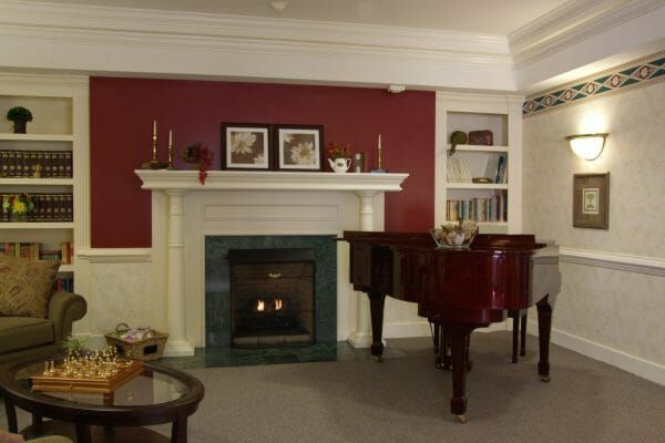 Fireplace and grand piano in the Charter Senior Living of Williamsburg community living room