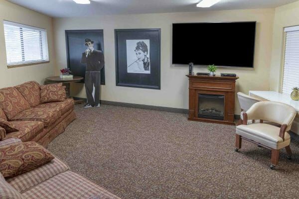 Entertainment room with big screen tv, movie posters, loveseat and chair at The Oakmont