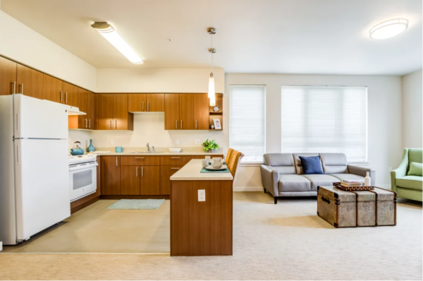 The kitchen and living room in a model apartment at Merrill Gardens at Auburn, separated by a breakfast bar