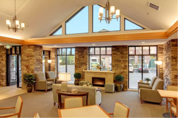 A fireside lounge with a wall of windows at Merrill Gardens at Tacoma