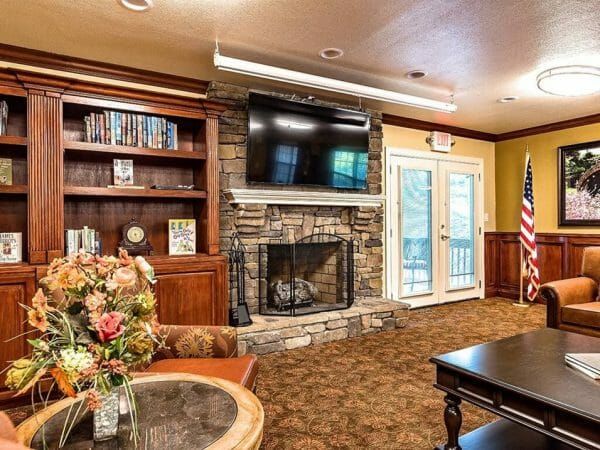 Pacifica Senior Living Heritage Hills community living room with large stone fireplace and wall mounted tv