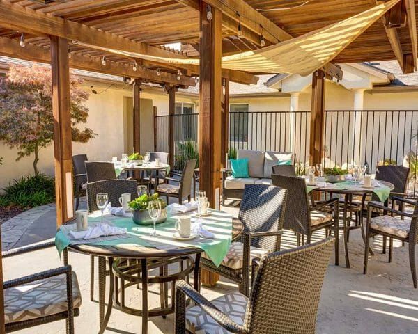 Dining tables under the Paramount Court Senior Living outdoor trellis