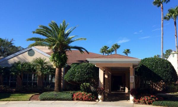 Savannah Cove of Maitland covered walkway up to entrance with royal palm tree and bright blue sky