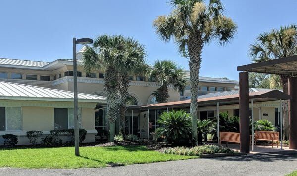 Front entrance on a sunny day at Savannah Grand of Amelia Island with long covered walkway and large palm trees in front