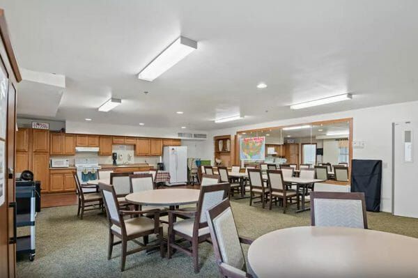 Tables and chairs in front of a community kitchen area in Seaton Voorhees' activity room