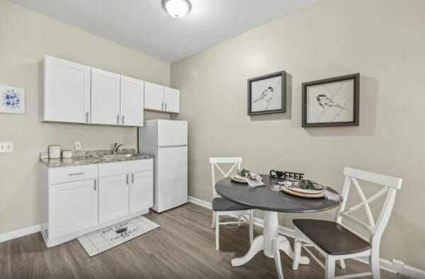 Seaton Voorhees' model apartment dining and kitchenette area, with a small table set for two, and white cabinets in the kitchenette