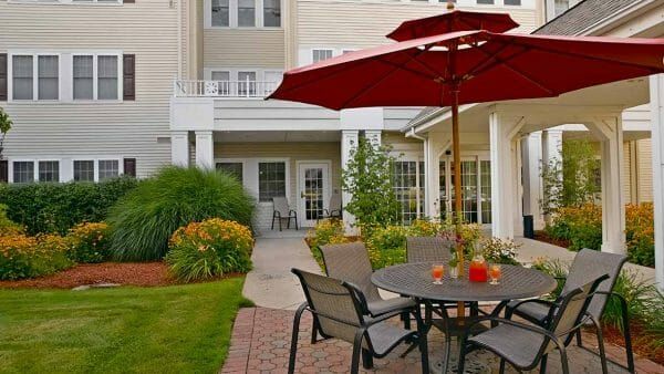 Red umbrella tables in the Atria Greenridge Place outdoor courtyard