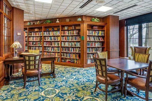 Brookdale Lisle reident library with book filled shelves and wood furniture