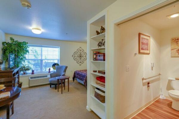 Model home includes bathroom area with shelves, bed, chair at Orchard Park