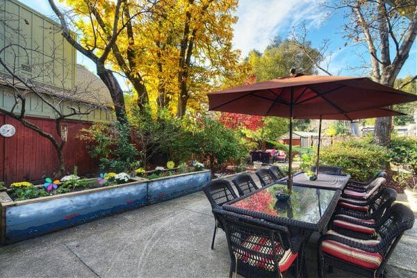 Dining tables with orange umbrellas on the WindChime of Marin Memory Care patio