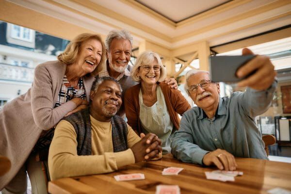 Group of cheerful seniors taking a selfie at a card table