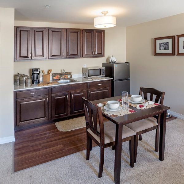 A dining table for two and the kitchenette in a model apartment at Brooklyn Pointe Assisted Living & Memory Care