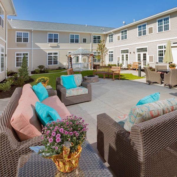 Plentiful seating on wicker chairs with colorful cushions in Brooklyn Pointe Assisted Living & Memory Care's courtyard