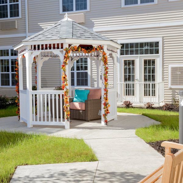 A white gazebo with seating in the courtyard at Brooklyn Pointe Assisted Living & Memory Care