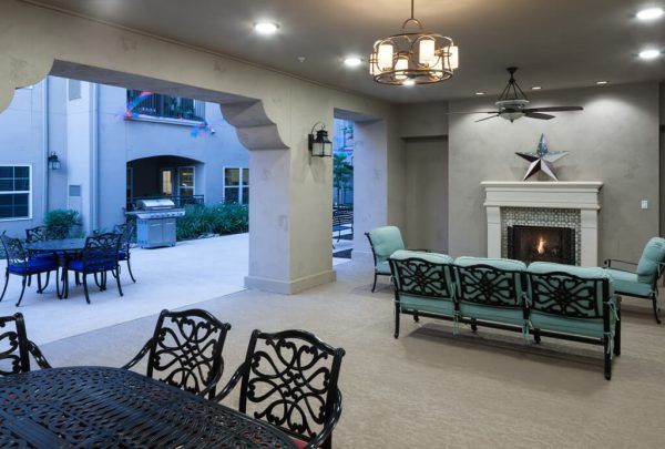 An outdoor, covered living room with a fireplace that's adjacent to a patio and grilling area at Franklin Park Alamo Heights
