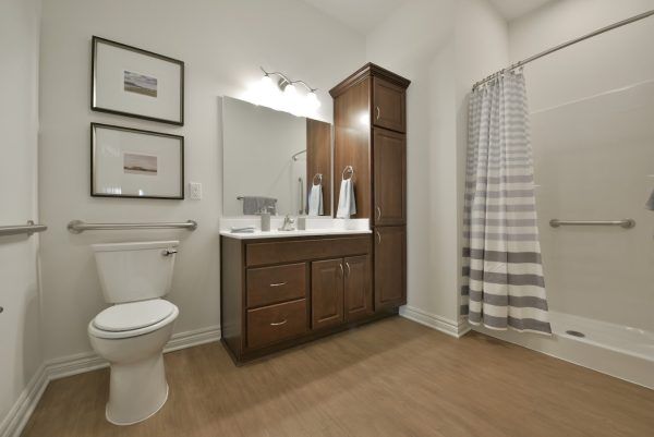 A model apartment bathroom at Rose Senior Living Beachwood, with safety bars near the commode and in the walk-in shower