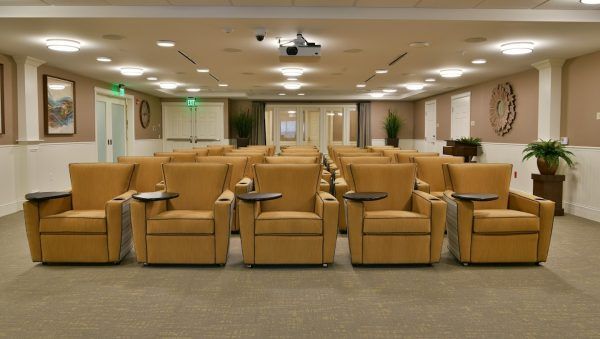 Theater seating with built-in tray and cup holders in Rose Senior Living Beachwood's media room
