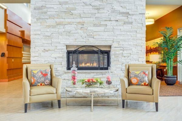 Two armchairs flanking a fireplace in Arlington Place Health Campus' lobby