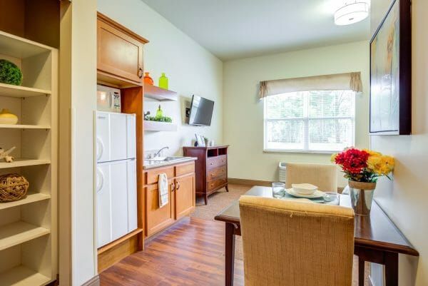 The dining table and kitchenette of an assisted living studio apartment at Arlington Place Health Campus