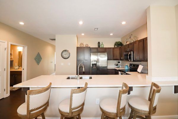 Traditions at North Willow's model villa kitchen, with stainless steel appliances and four stools at the peninsula
