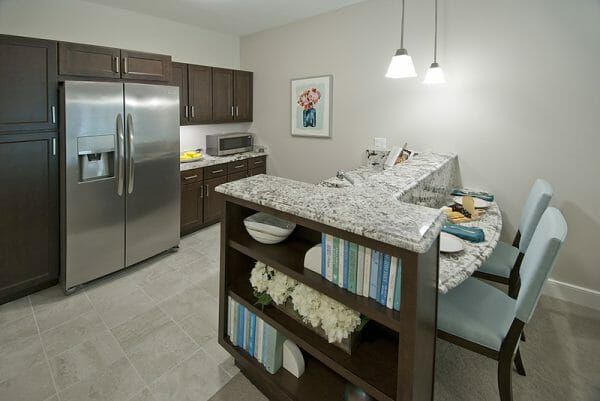 Allegro Harrington Park's model apartment kitchen, with stainless steel appliances. Pendant lights are over the breakfast bar, which has a built-in bookshelf at one end