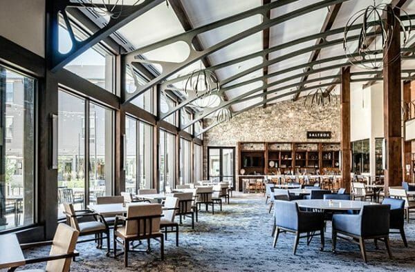 Thrive at Montvale's largest dining room, The Saltbox, which has a wall of windows, a dramatic, curved ceiling with metal beams and a bar at the back