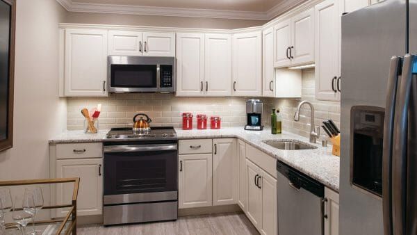 Cedar Crest Senior Living's model apartment kitchen, with white cabinets and countertops and stainless steel appliances