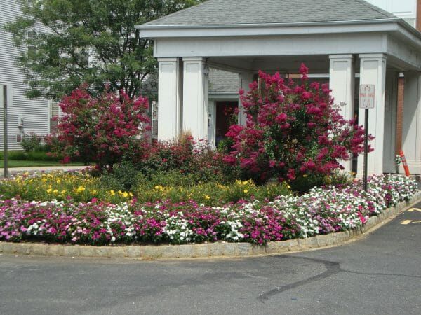 Colorful flowers in front of Monmouth Crossing Assisted Living's covered main entrance