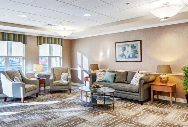 Heritage Run at Stadium Place great room with large gray couch and matching club chairs with two large picture windows with outdoor view