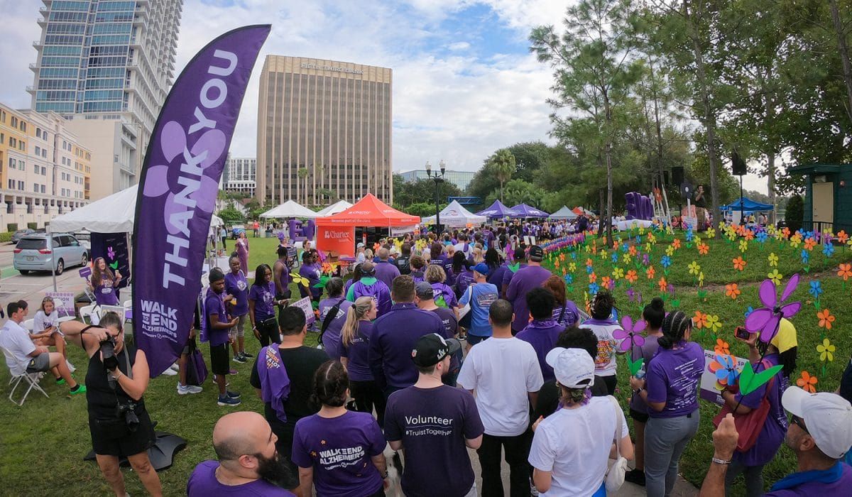 A large group of people attending a Alzheimer's walk wearing purple shirts