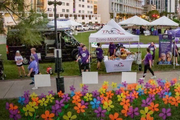 Vendor tents and colorful flowers lining a pathway at a Alzheimer's walk event